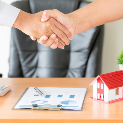 Side view hands of agent and client shaking hands after signed contract buy new apartment.